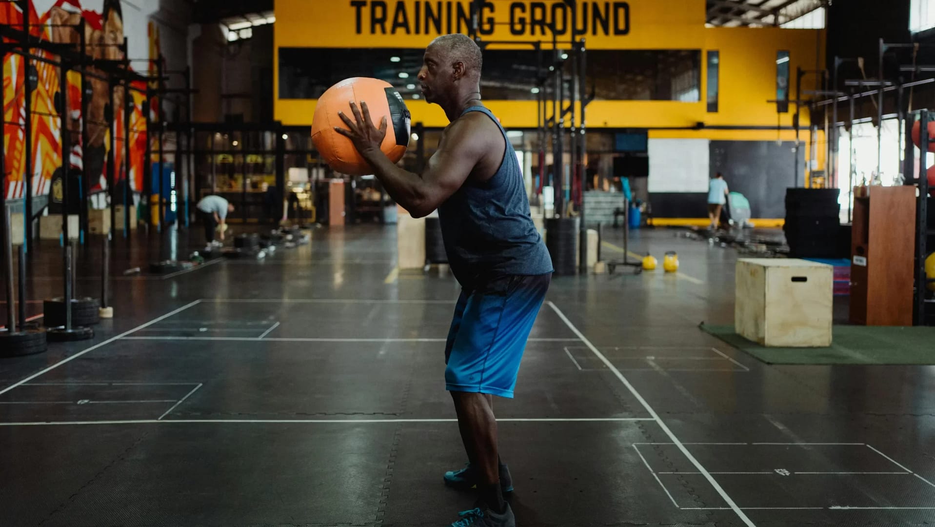 Homme réalisant un squat avec un medecine ball dans une salle d'entraînement fonctionnel.